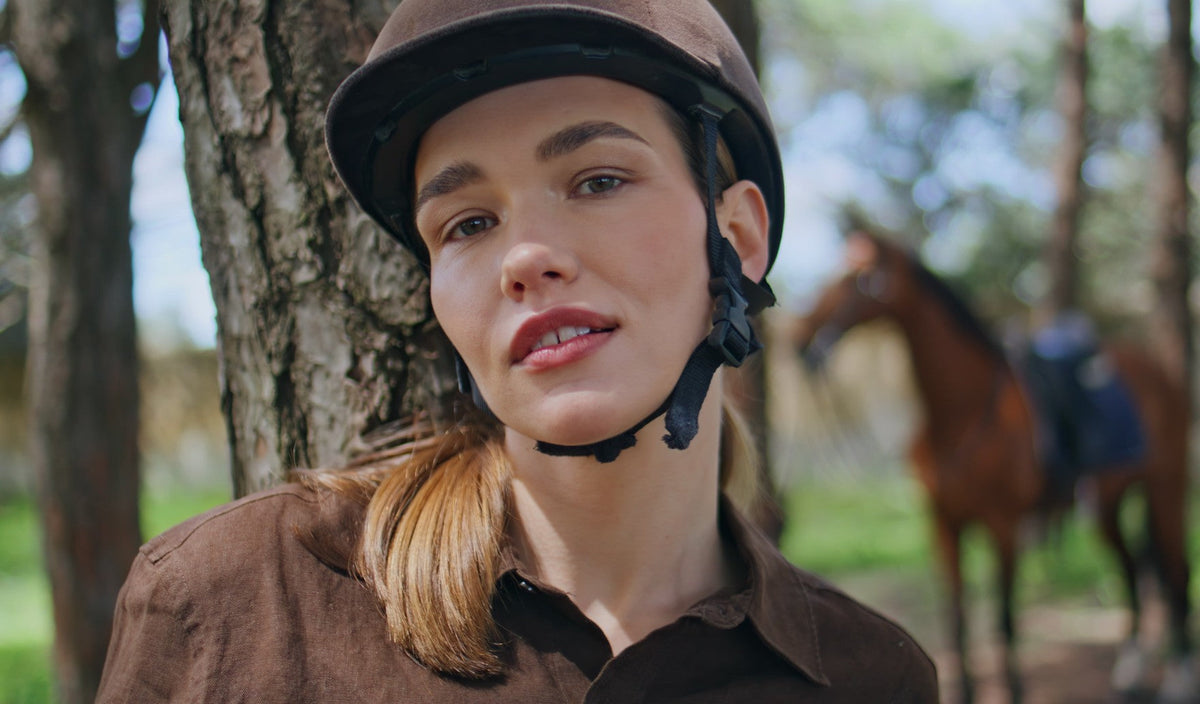 Riding helmet with its harness resting beside a saddle