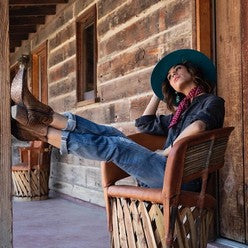 Woman lounging in chair with feet up on verandah post