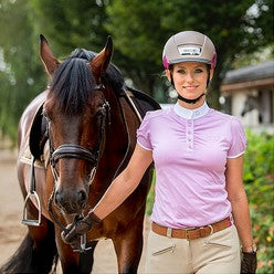 Lady in helmet, pink shirt and jodhpurs leading her horse