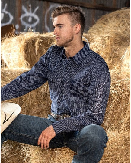 Man sitting on hay bale in jeans and wrangle shirt