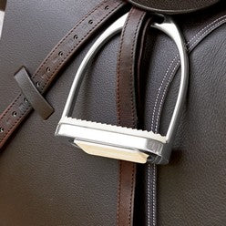close up of stirrup iron and leathers on saddle