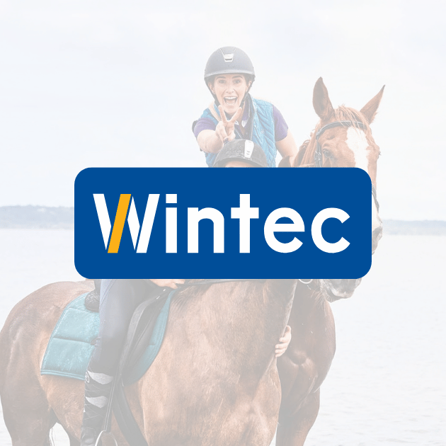 Wintec brand logo over a smiling rider on a bay horse at the beach