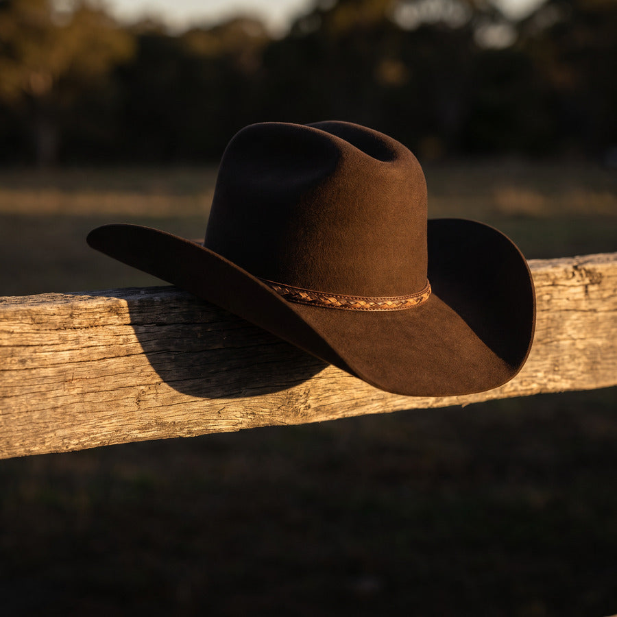 Brown felt wide brim hat resting on a timber rail