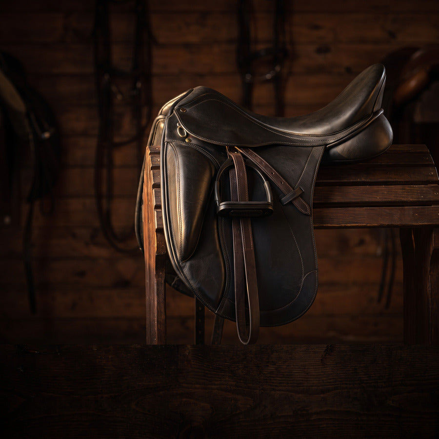 Leather english saddle resting on a saddle rack in a stable