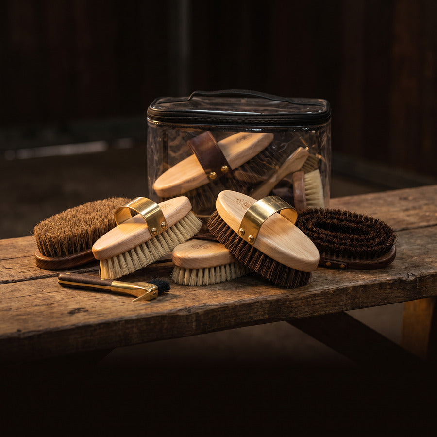 Horse grooming brushes in a glass jar on a timber bench