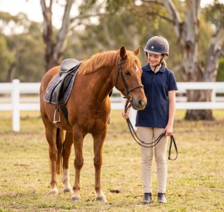 A young rider standing with a pony